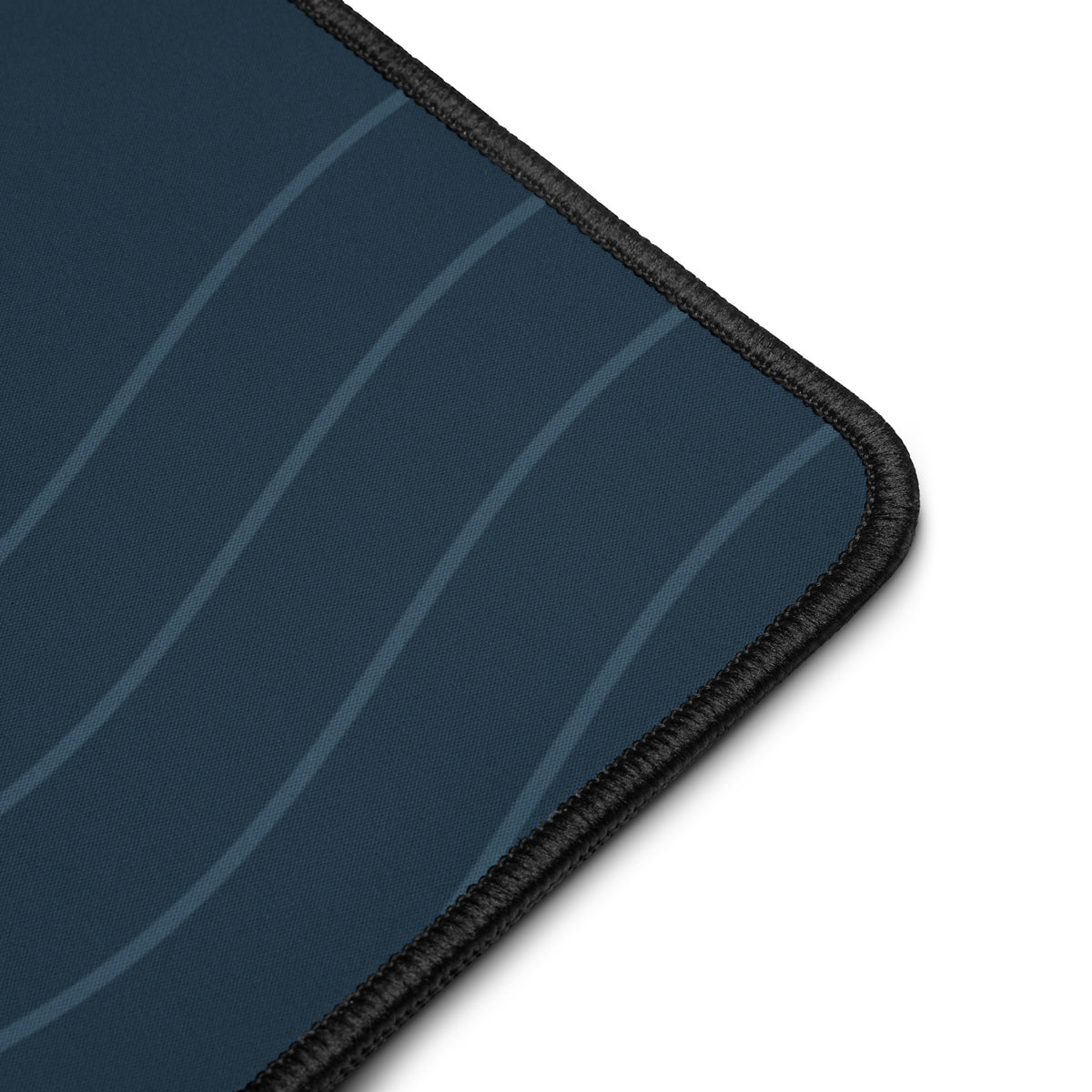 Digital close-up mockup of the navy Sarnaya Contour Desk Mat, showing its curved-line print, fabric surface and black stitched edge.