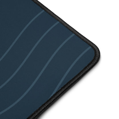 Digital close-up mockup of the navy Sarnaya Contour Desk Mat, showing its curved-line print, fabric surface and black stitched edge.
