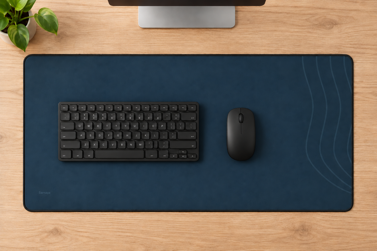 AI-generated overhead workspace illustration showing the navy Contour Desk Mat, a keyboard and a mouse on a wooden desk.